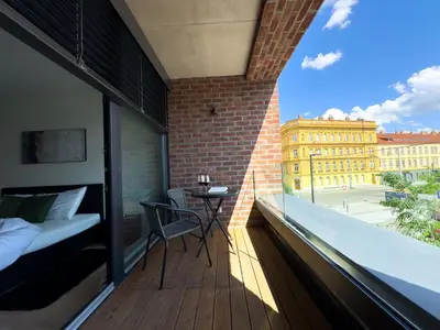 a room with a balcony with a bed and a table at Central Riverside Apartment - Free Parking in Prague