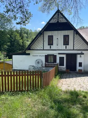 a white house with a fence in front of it at Penzion Černý Mlýn in Dubá