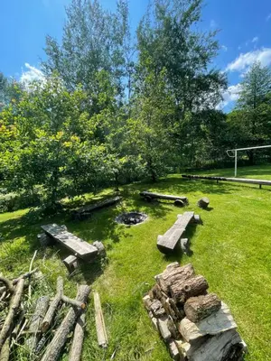 a garden with logs and a fire pit in the grass at Penzion Černý Mlýn in Dubá