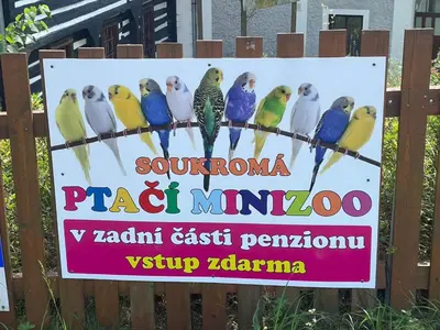 a sign on a fence with colorful birds on it at Penzion Černý Mlýn in Dubá