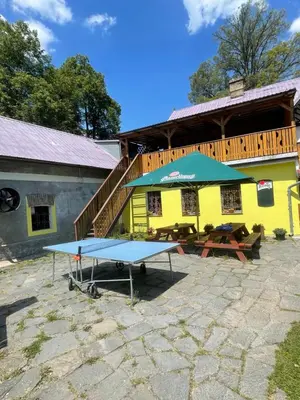 a ping pong table in front of a yellow building at Penzion Černý Mlýn in Dubá