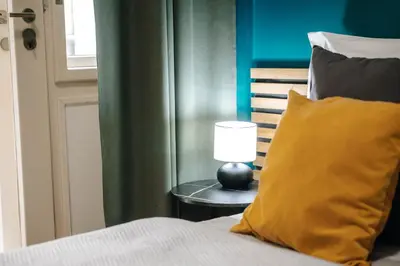 a bed with a yellow pillow and a lamp on a table at Cityscape Charm Spacious 3 Bedroom Haven for 7 in Prague