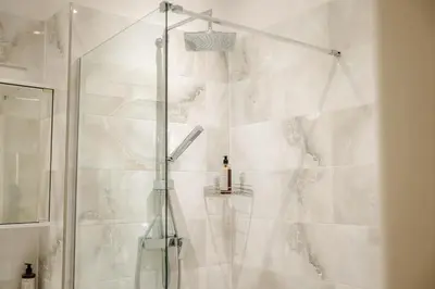 a shower with a glass door in a bathroom at Cityscape Charm Spacious 3 Bedroom Haven for 7 in Prague