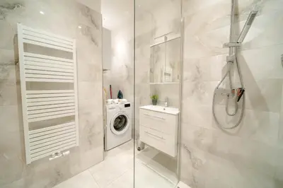a bathroom with a shower and a washing machine at Cityscape Charm Spacious 3 Bedroom Haven for 7 in Prague