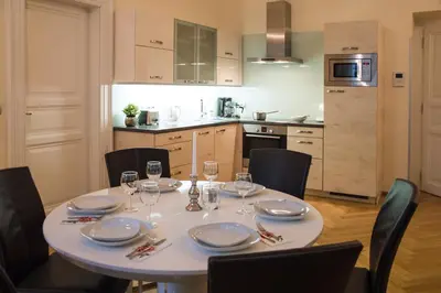 a dining room table with chairs and a white table set with wine glasses at Modern Apartment Všehrdova in Prague