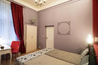 a bedroom with a bed and a table and a red chair at Design Apartment Havelska in Prague