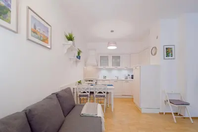 a living room with a couch and a table and a kitchen at Modern Apartment Charvátova in Prague