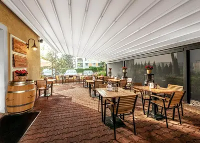 a restaurant with wooden tables and chairs and windows at Prague Hotel Carl Inn restaurant & Free Parking in Prague