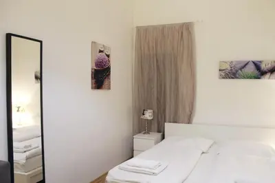 a white bedroom with a bed and a mirror at Modern Apartment Ve Smečkách 28 in Prague