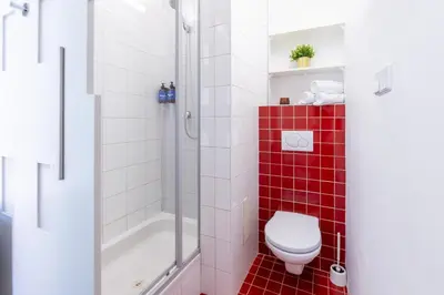a bathroom with a toilet and a shower with red tile at Prague Days - Studio with Netflix and Apple TV next to Park in Lesser Town in Prague