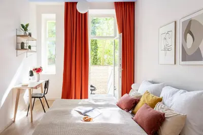 a bedroom with a bed and a window with red curtains at Prague Days - 3BDR Apartments with Terrace in Residential Vinohrady in Prague