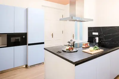 a kitchen with white cabinets and a black counter top at Prague Days - 3BDR Apartments with Terrace in Residential Vinohrady in Prague