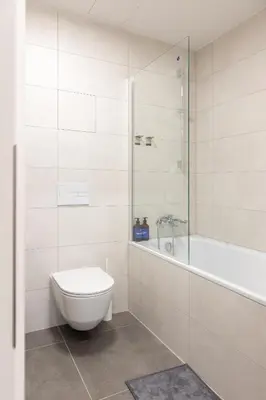 a white bathroom with a toilet and a bath tub at Prague Days - Modern Apartment with Terrace and AC in Karlín in Prague