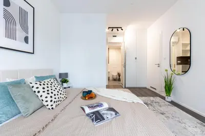 a white bedroom with a bed with a mirror at Prague Days - Modern Apartment with Terrace and AC in Karlín in Prague