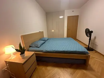 a bedroom with a bed with blue sheets and a fan at Vikys Apartment in Prague