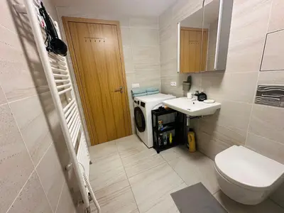 a bathroom with a toilet and a sink and a washing machine at Vikys Apartment in Prague