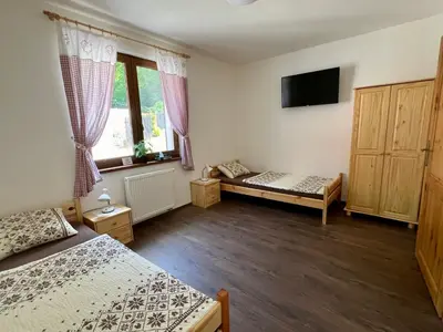 a bedroom with two beds and a flat screen tv at Chalupa nad rybníkem in Straškov