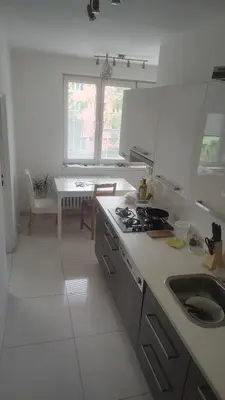 a white kitchen with a sink and a stove at Nomads room nearest forest Kamýk in Prague