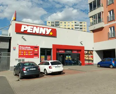 two cars parked in a parking lot in front of a pharmacy at Nomads room nearest forest Kamýk in Prague