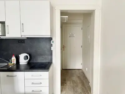 a kitchen with white cabinets and a door to a hallway at JZP studio apartment in Prague