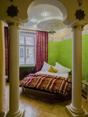 a bedroom with a bed with green walls and columns at 1000 and 1 night in Prague city center in Prague