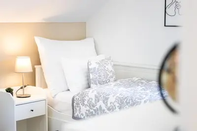 a bedroom with a bed with white pillows and a mirror at Chata Kloučka Stříbrná Skalice in Stříbrná Skalice