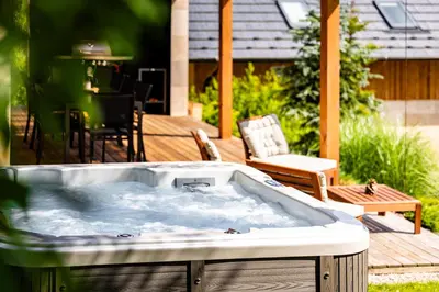 a hot tub on a deck with a table and chairs at Chata Kloučka Stříbrná Skalice in Stříbrná Skalice