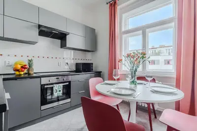 a kitchen with a white table and red chairs at 3-bedroom apartment for family in Prague