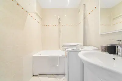 a white bathroom with a tub and a sink at 3-bedroom apartment for family in Prague