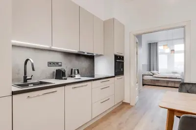 a kitchen with white cabinets and a table and a bed at One bedroom Apartment at Sokolovska in Prague
