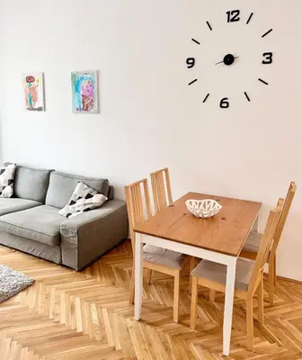 a living room with a table and a clock on the wall at Viaduct View Apartment in Prague