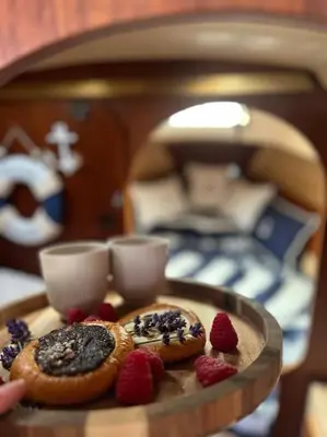 a tray with donuts and strawberries on a table with a bed at Ubytování na plachetnici in Živohošť