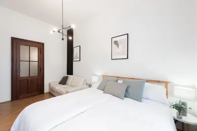 a white bedroom with a bed and a couch at Prague City vibe apartment in Prague