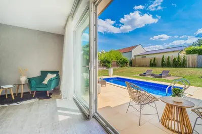 a patio with a pool and chairs and a table at Vila Sara s bazénem a infrasaunou na kraji Prahy in Zbuzany