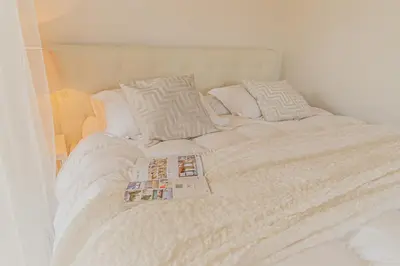 a white bed with a book on top of it at Vila Sara s bazénem a infrasaunou na kraji Prahy in Zbuzany