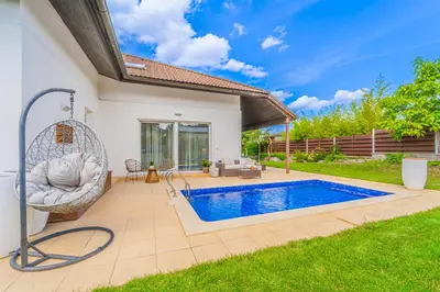a swimming pool in a backyard with a swing at Vila Sara s bazénem a infrasaunou na kraji Prahy in Zbuzany