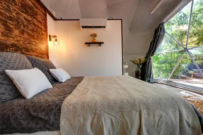 a bedroom with a large bed with a large window at Tiché místo Glamping in Slapy
