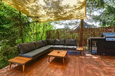 a couch on a deck with a table and a grill at Tiché místo Glamping in Slapy