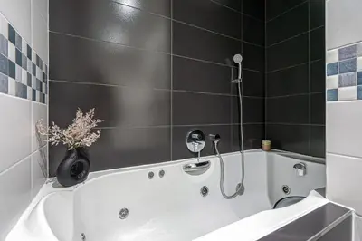 a bathroom with a white tub and a black tile wall at Oasis Apartments at Charles Square in Prague