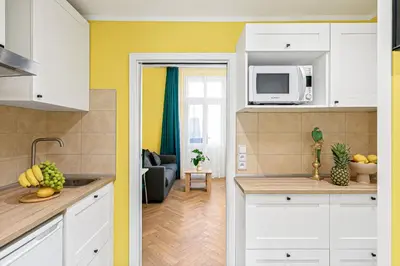 a kitchen with white cabinets and a living room at Oasis Apartments at Charles Square in Prague