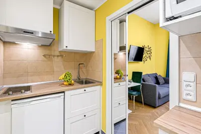 a kitchen with white cabinets and a living room at Oasis Apartments at Charles Square in Prague