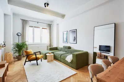 a living room with a green couch and a tv at Luxury riverside apartment in Prague