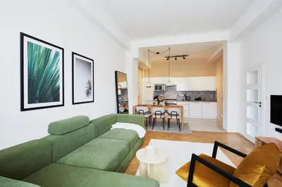 a living room with a green couch and a kitchen at Luxury riverside apartment in Prague