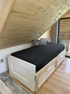 a bed in a room with a wooden ceiling at Mini Apartman - G - Vyhlídka nad řekou in Zámky