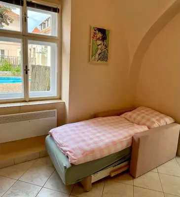 a small bed in a room with a window at Apartmán Dominikánská in Litoměřice