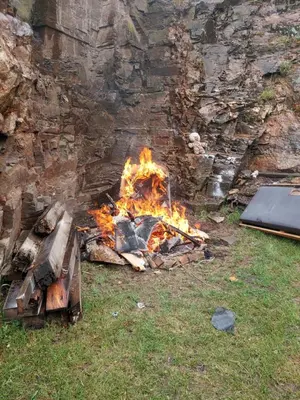 a fire in the grass next to a stone wall at Chalupa pod hradem Talmberk in Samopše