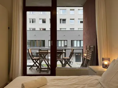 a bedroom with a bed and a balcony with a table and chairs at Apartment A l Modern Stay with Parking in Prague