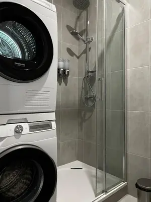 a shower with a glass door next to a washing machine at Apartment B l Modern Stay with Parking in Prague
