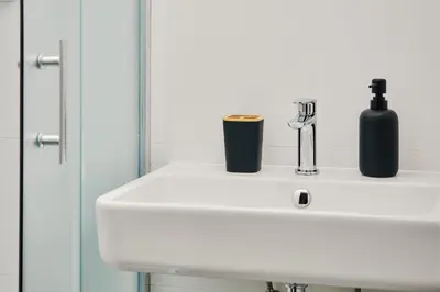 a white sink with a black bottle and a mirror at Teytz Apartments in Prague