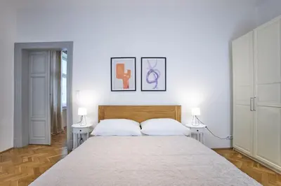 a white bedroom with a large bed with two lamps at Wenceslas Square Residence in Prague
